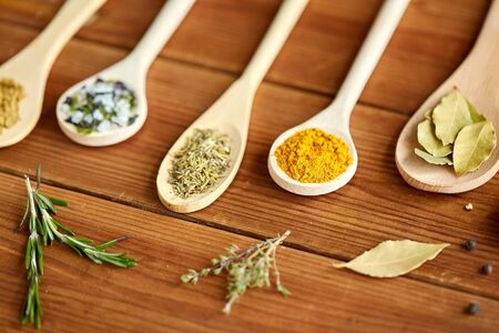 spoons with spices and salt on wooden table