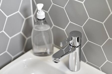 close up of water tap with liquid soap on sink