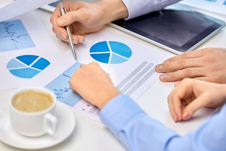 corporate and people concept - close up of business team hands with pens and charts at office