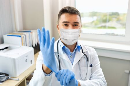 doctor in medical mask wearing gloves at hospitalの写真素材