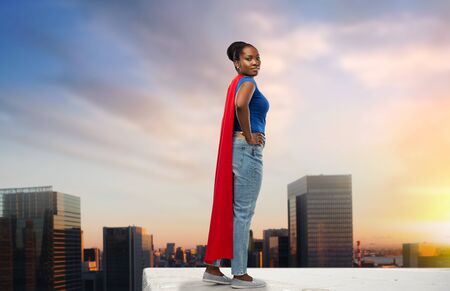 happy african american woman in red superhero capeの写真素材