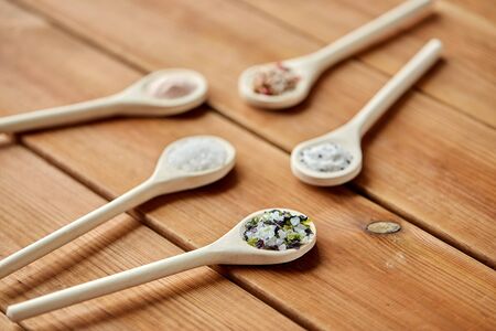 food, culinary and unhealthy eating concept - spoons with salt and spices on wooden tableの写真素材