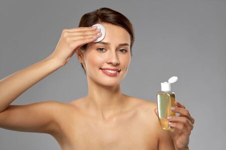 young woman with toner or cleanser and cotton pad