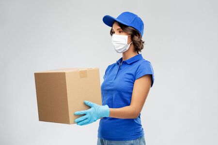 delivery woman in face mask holding parcel boxの写真素材