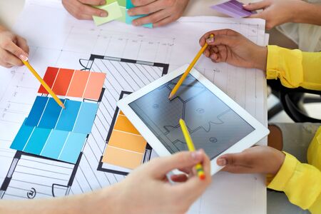design and people concept - creative team of interior designers with blueprint on tablet pc computer screen and color palettes working at officeの写真素材