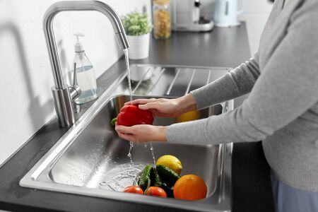 Woman washing fruits and vegetables in kitchenの写真素材