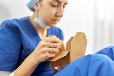 sad doctor or nurse eating takeaway food from box