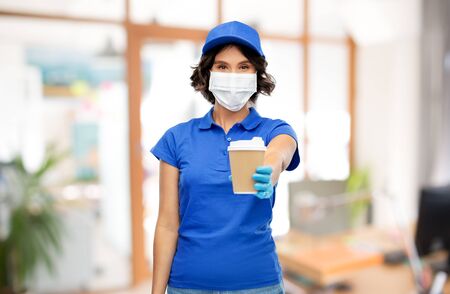 saleswoman in face mask with coffee cup at officeの写真素材