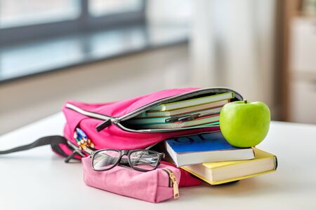 backpack, apple and school supplies on table