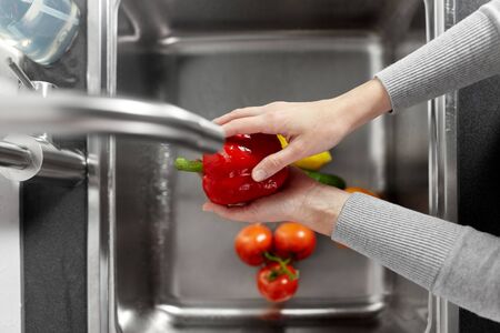 woman washing fruits and vegetables in kitchenの写真素材