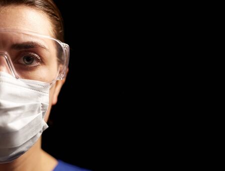 female doctor or nurse in goggles and face maskの写真素材