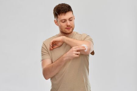 young man applying pain medication to his elbow