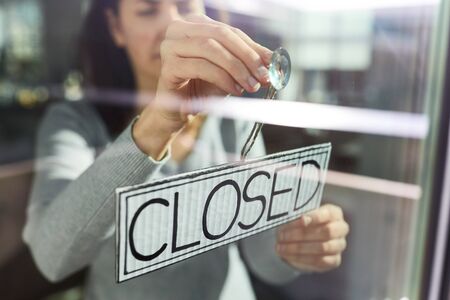 woman hanging banner with closed word on doorの写真素材