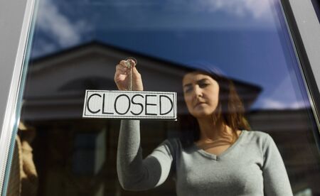 woman hanging banner with closed word on door