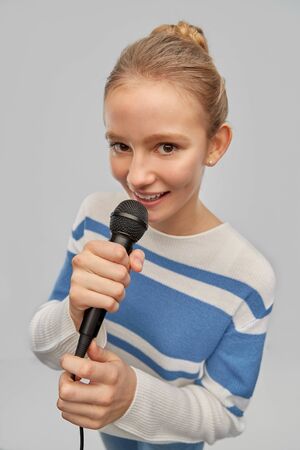 smiling teenage girl with microphone singingの写真素材
