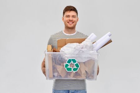 smiling young man sorting paper wasteの写真素材
