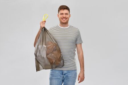 smiling man holding trash bag with paper wasteの写真素材