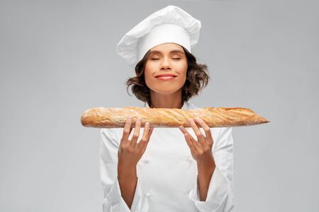 happy female chef with french bread or baguetteの写真素材