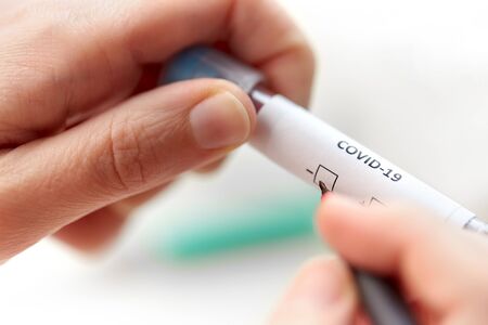 hand holding beaker with coronavirus blood test