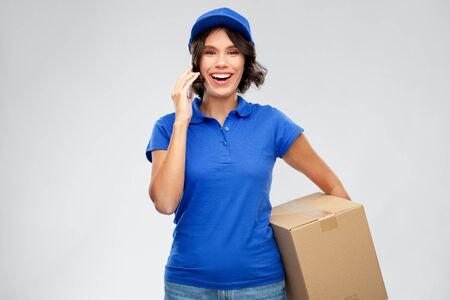 delivery girl with parcel box calls on smartphoneの写真素材