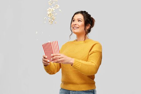 happy smiling young woman playing with popcornの写真素材