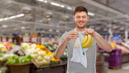 smiling man putting bananas into reusable net bag