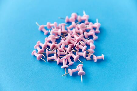 heap of pink office pins on blue background