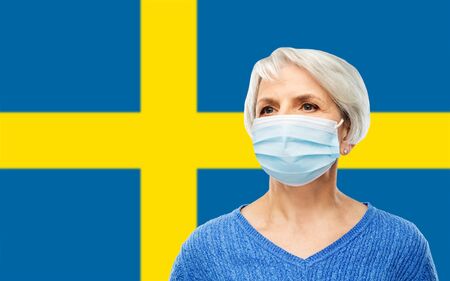 senior woman in mask over flag of swedenの写真素材