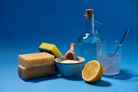 natural cleaning stuff and eco living concept - washing soda and lemon, sponge, soap, bottle of...