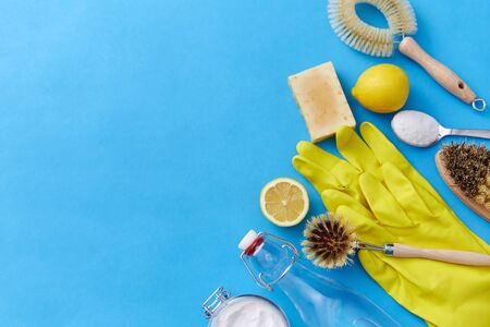 natural cleaning stuff and eco living concept - bottle of vinegar, lemons, rubber gloves, washing soda with soap and brush on blue backgroundの写真素材