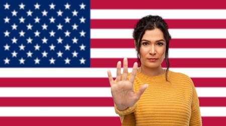 woman showing stop gesture over flag of americaの写真素材