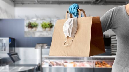 woman with food in paper bag, face mask and glovesの写真素材