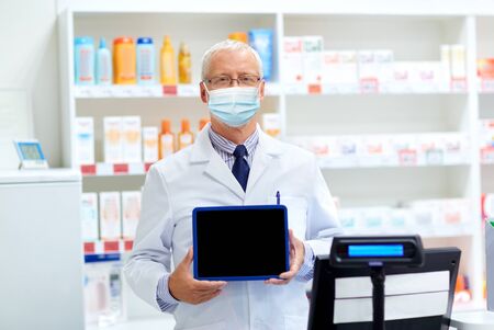 old apothecary in mask with tablet pc at pharmacy