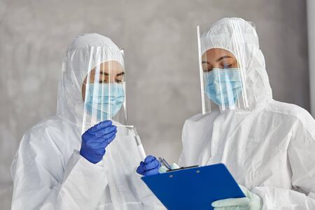 doctors in medical mask and shield with clipboard