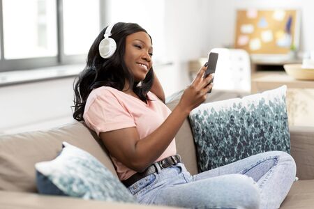 woman with smartphone listening to music at homeの写真素材