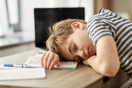 tired student boy sleeping on desk at homeの写真素材
