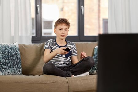 boy with remote control watching tv at homeの写真素材