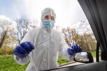 healthcare worker making coronavirus test at car