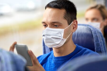 man in mask using smartphone in travel busの写真素材