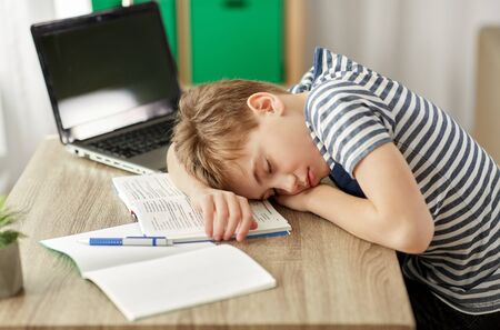 tired student boy sleeping on desk at homeの写真素材