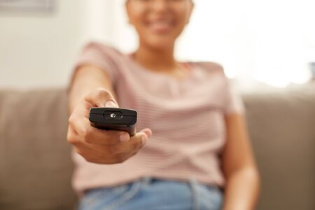 happy african american woman watching tv at homeの写真素材