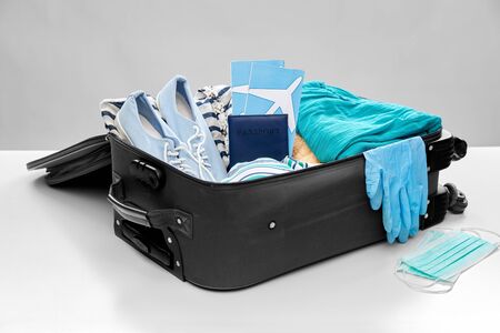 travel bag packed with clothes, gloves and masks