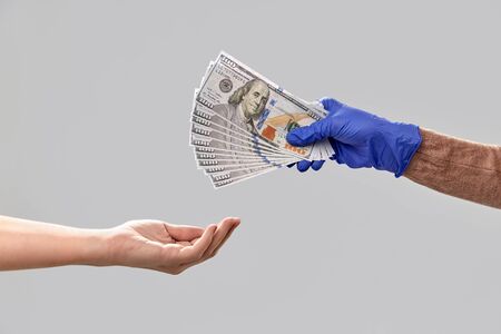 close up of hand in medical glove giving moneyの写真素材