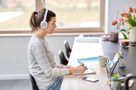 woman in headphones with tablet pc working at home