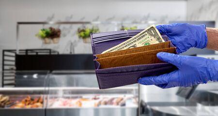 close up of hands in gloves with dollar in wallet