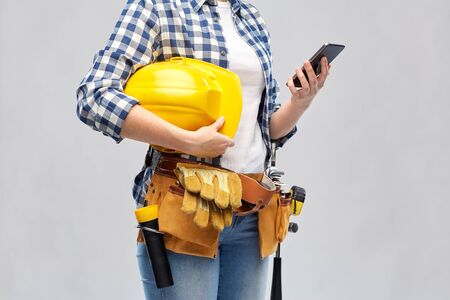 woman or builder with phone and working tools