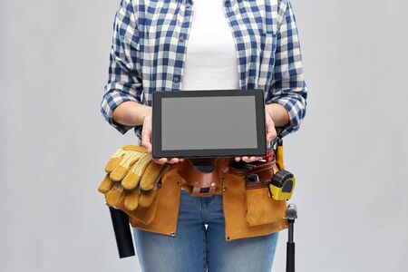Woman builder with working tools showing tablet pcの写真素材