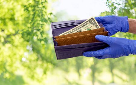 close up of hands in gloves with dollar in wallet