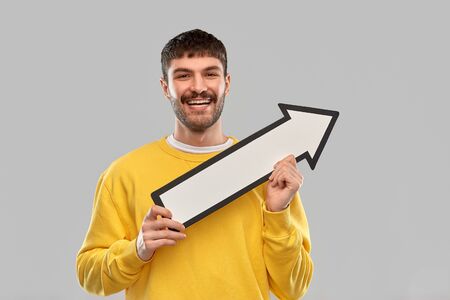 smiling man holding big arrow pointing to right
