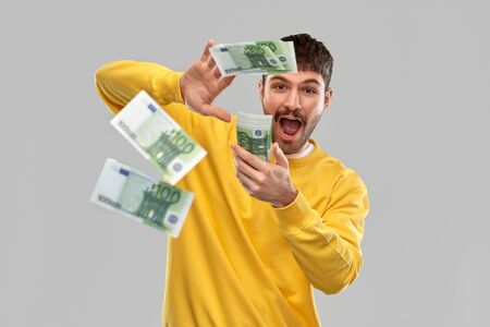 happy man in yellow sweatshirt pouring money